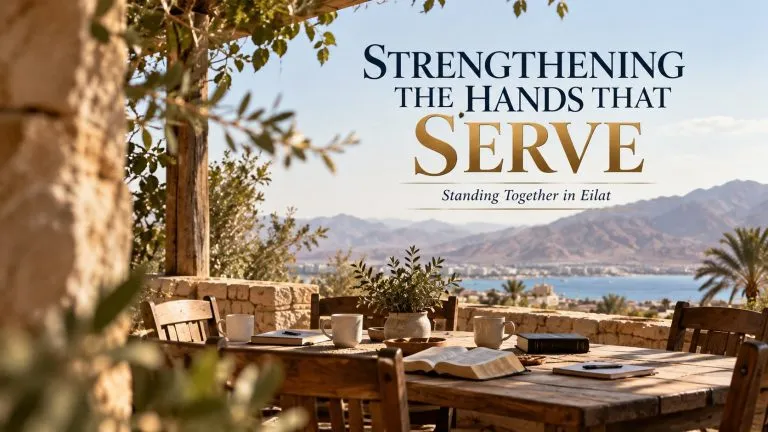 Strengthening the Hands That Serve – Standing Together in Eilat, title graphic over a table with Bibles overlooking Eilat and the Red Sea